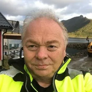 Mann med arbeidsklær og maskiner i bakgrunn